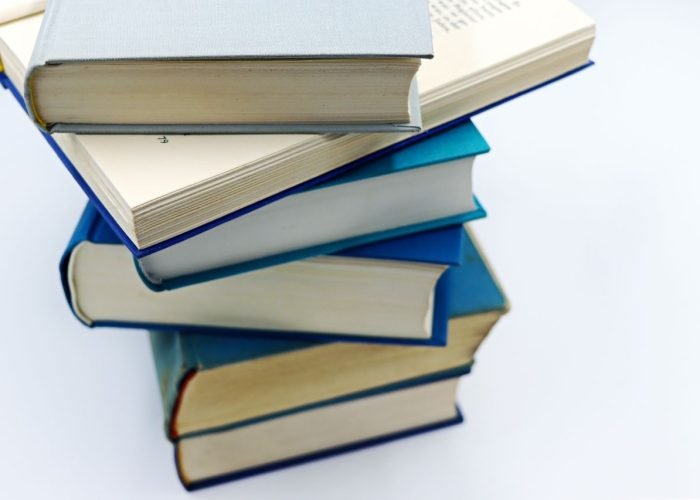 A pile of books with blue covers on a white background, symbolizing education and knowledge.
