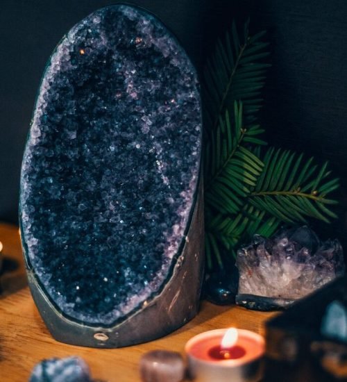 Serene scene with a large amethyst geode, teardrop candles, and lush greenery. Perfect for spa and relaxation themes.