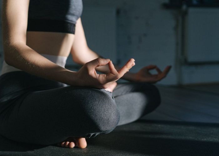 Woman practicing meditation on a yoga mat indoors, focusing on mindfulness and relaxation.